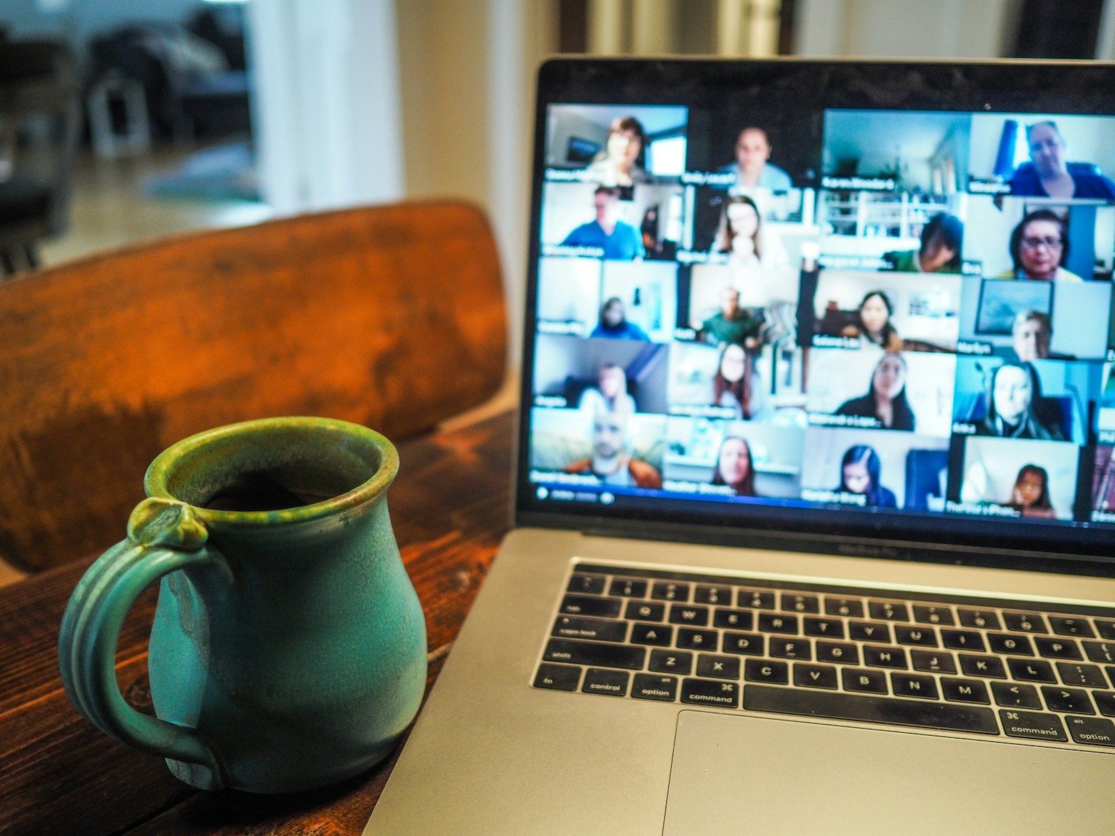 Person on a video call with multiple colleagues visible on laptop screen, representing virtual meeting software